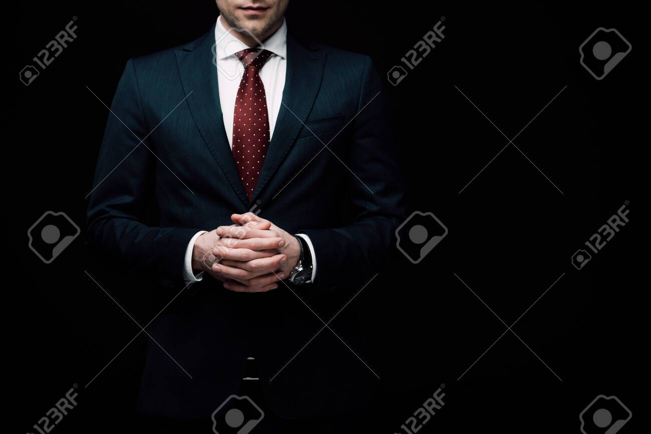 partial view of confident businessman standing with clenched hands isolated on black, human emotion and expression concept - 128147259 partial view of confident businessman standing with clenched hands isolated on black, human emotion and expression concept - 128147259