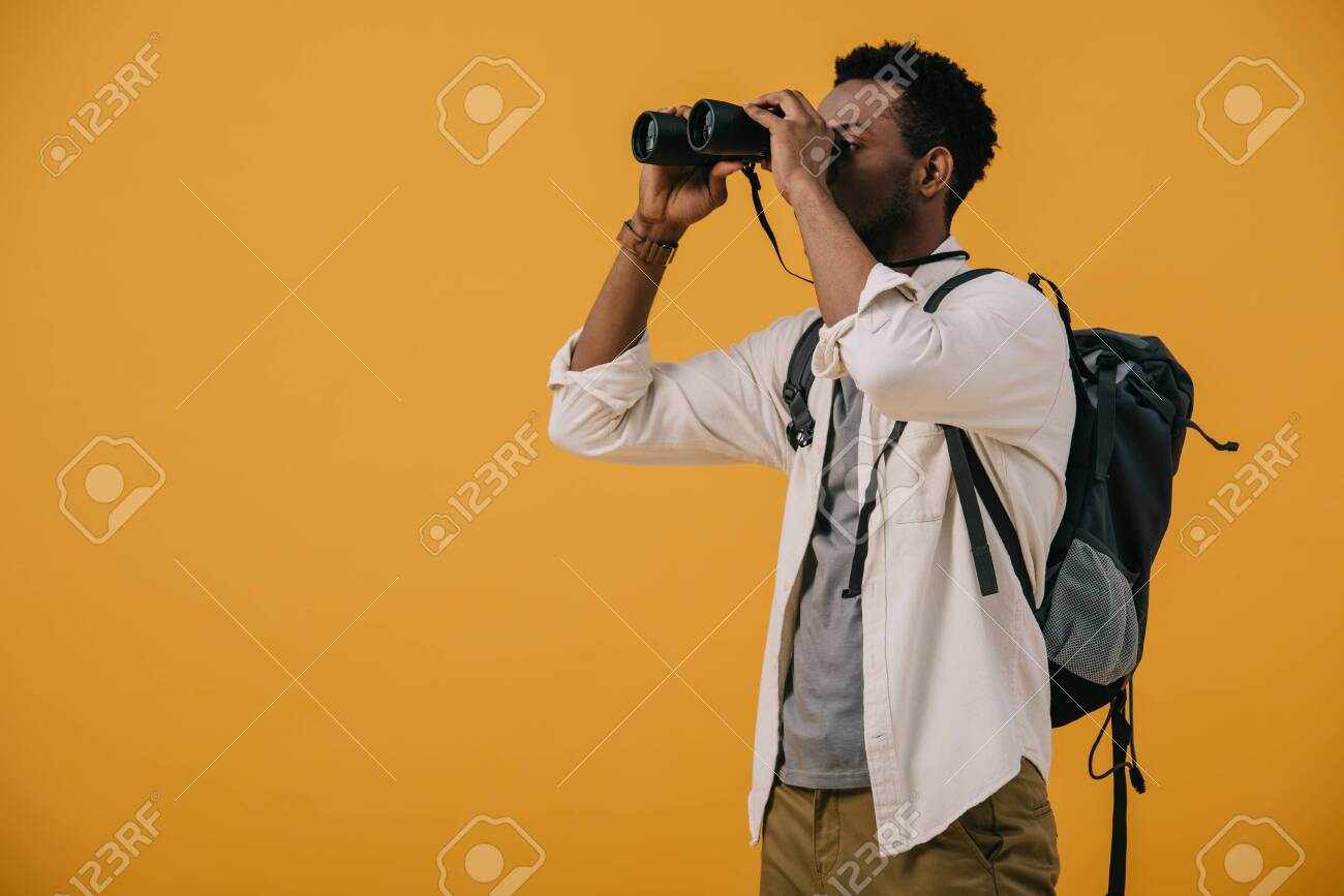 african american man looking through binoculars isolated on orange - 130335953 african american man looking through binoculars isolated on orange - 130335953