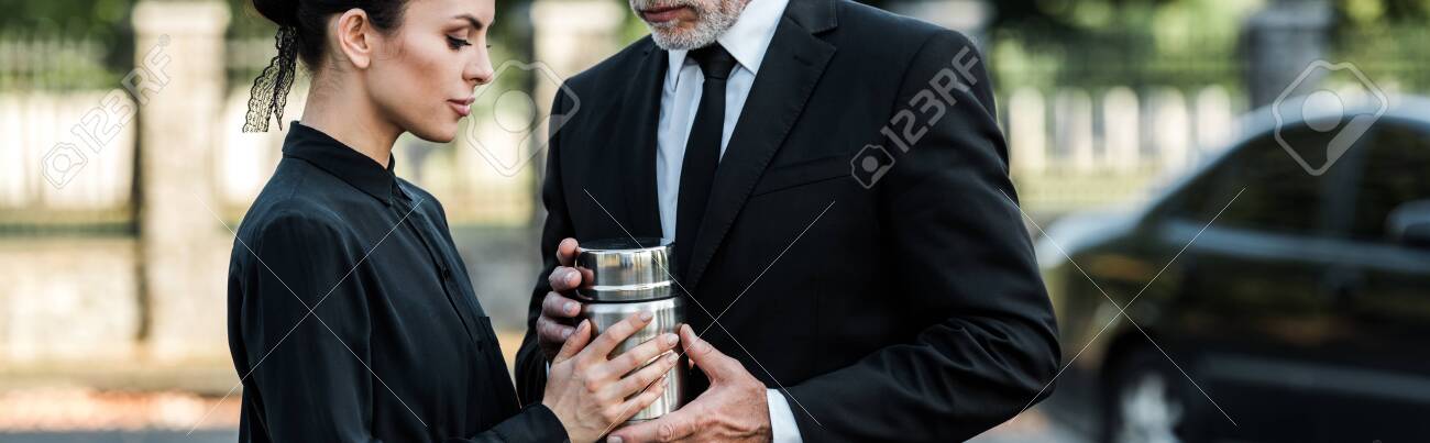 panoramic shot of man and woman holding mortuary urn - 130484971 panoramic shot of man and woman holding mortuary urn - 130484971
