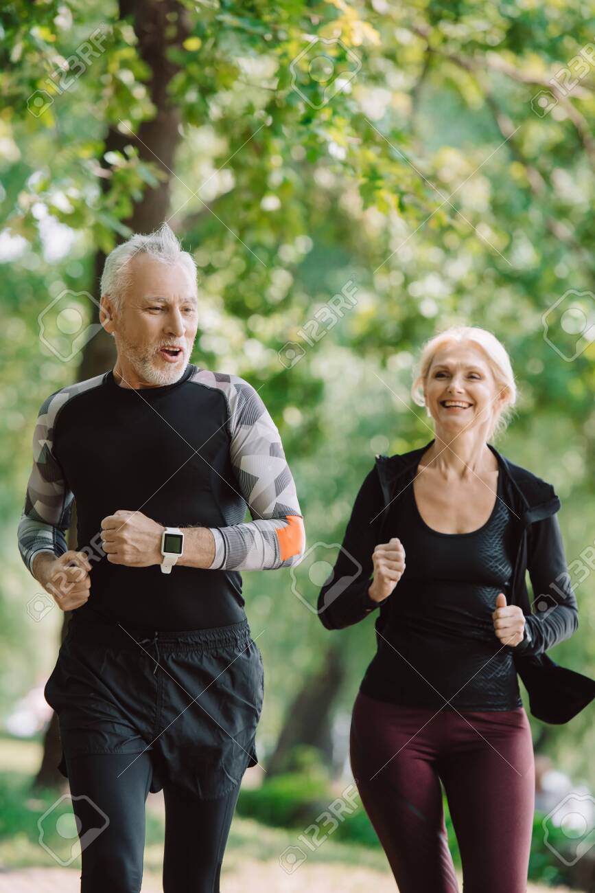 cheerful mature sportsman and sportswoman running together in park - 130486280 cheerful mature sportsman and sportswoman running together in park - 130486280
