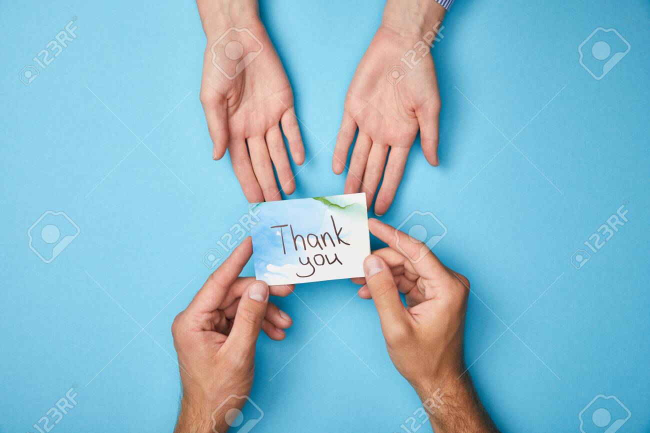 cropped view of man giving greeting card with thank you lettering to woman on blue background - 130575427 cropped view of man giving greeting card with thank you lettering to woman on blue background - 130575427