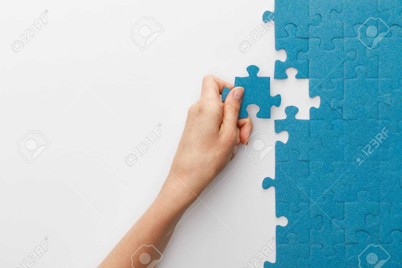 cropped view of woman attaching blue jigsaw puzzle on white background - 130574728 cropped view of woman attaching blue jigsaw puzzle on white background - 130574728