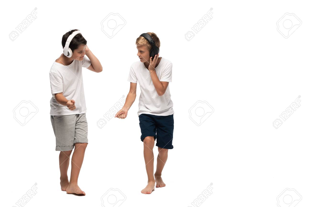 two brothers listening music in headphones and dancing on white background - 134010884 two brothers listening music in headphones and dancing on white background - 134010884