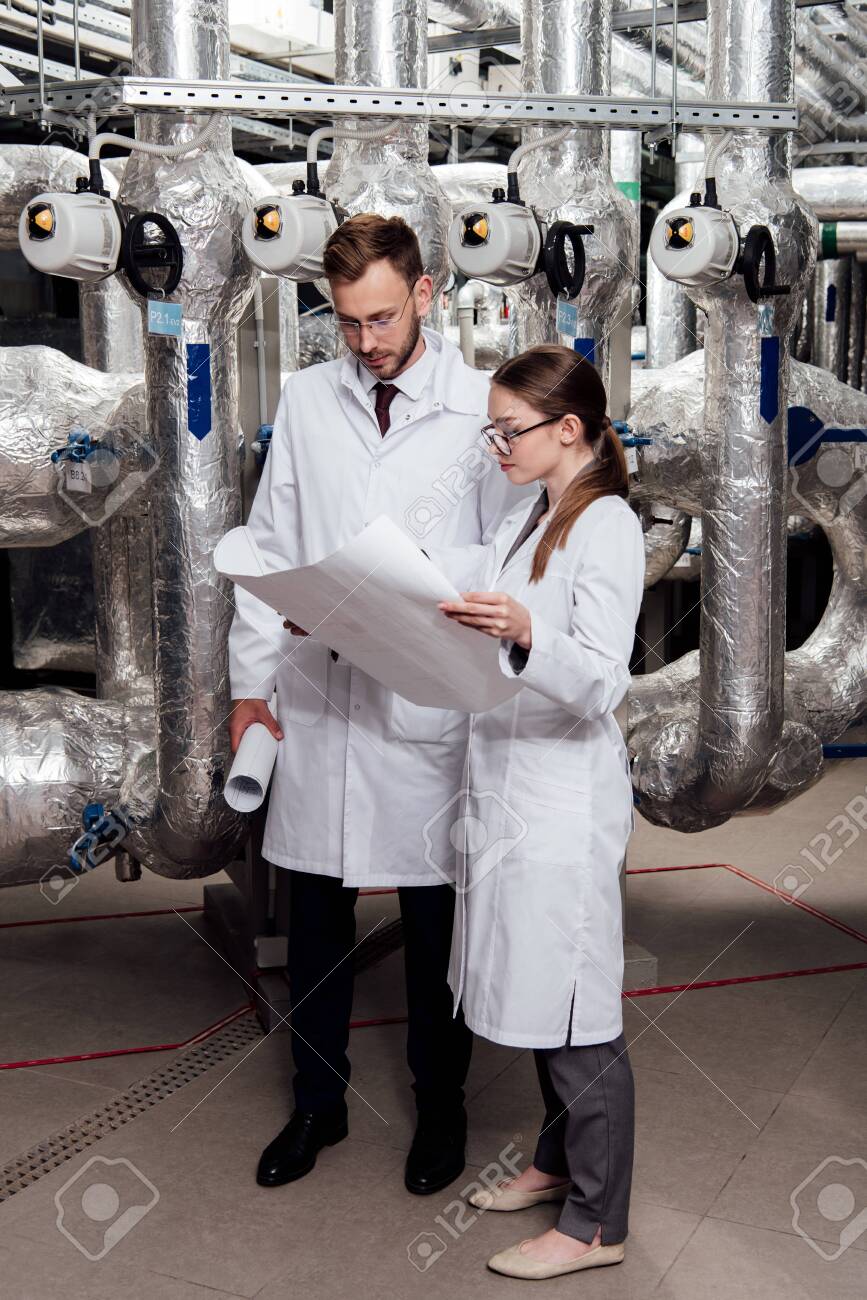 engineers in glasses and white coats looking at blueprint near air compressor system - 134011065 engineers in glasses and white coats looking at blueprint near air compressor system - 134011065