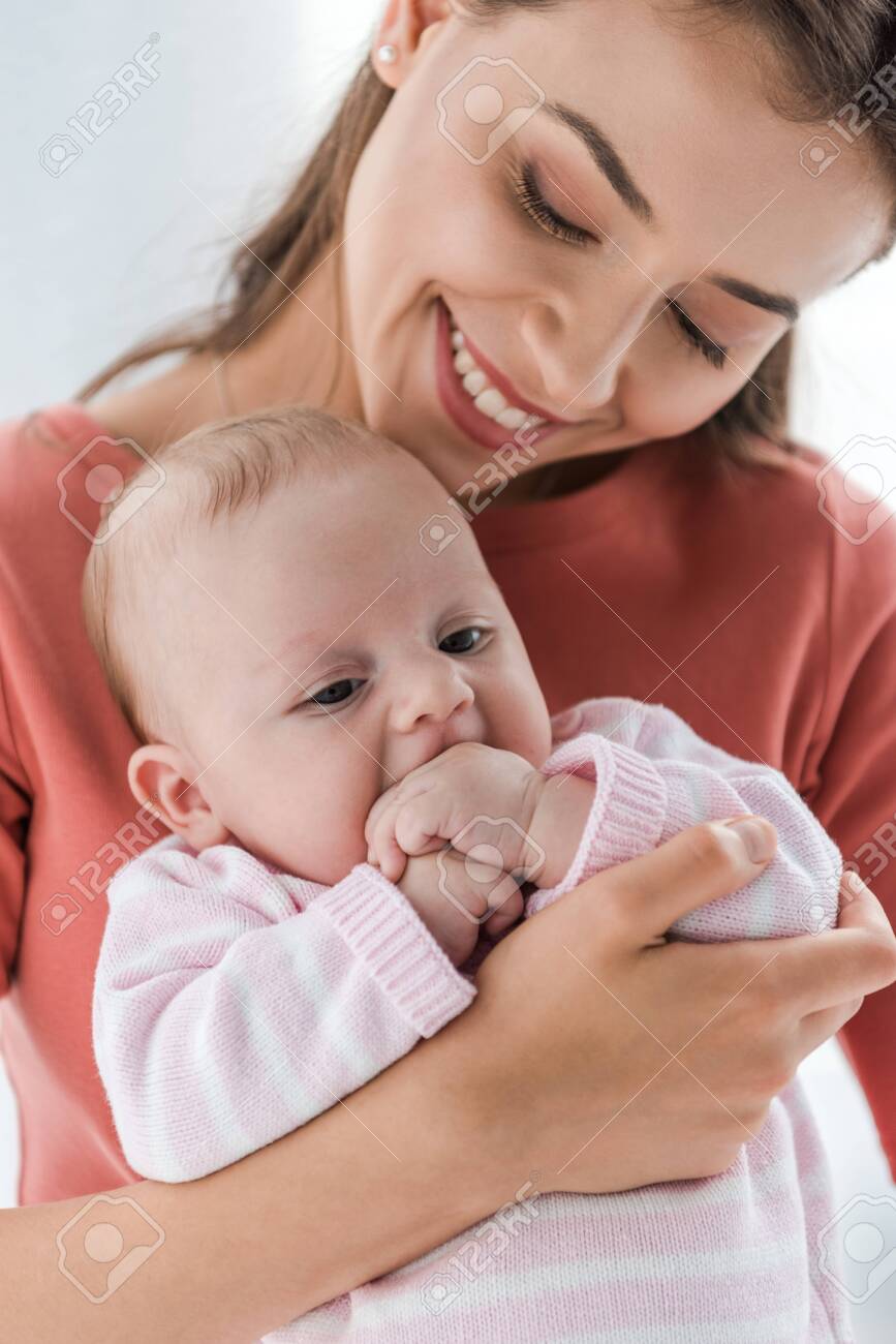 cheerful mother holding in arms adorable infant daughter at home - 134012961 cheerful mother holding in arms adorable infant daughter at home - 134012961