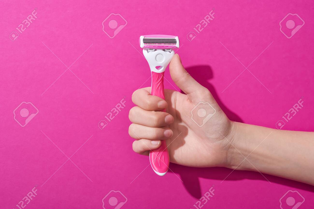 cropped view of woman holding razor on pink background - 134812848 cropped view of woman holding razor on pink background - 134812848