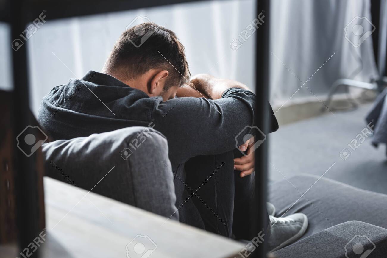 back view of man with panic attack crying and hugging legs in apartment - 134985245 back view of man with panic attack crying and hugging legs in apartment - 134985245