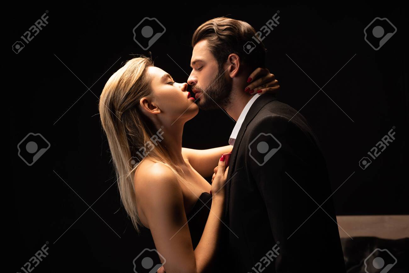 Passionate couple leaning in for a deep kiss in dramatic dark lighting – the electric start of steamy sex scenes