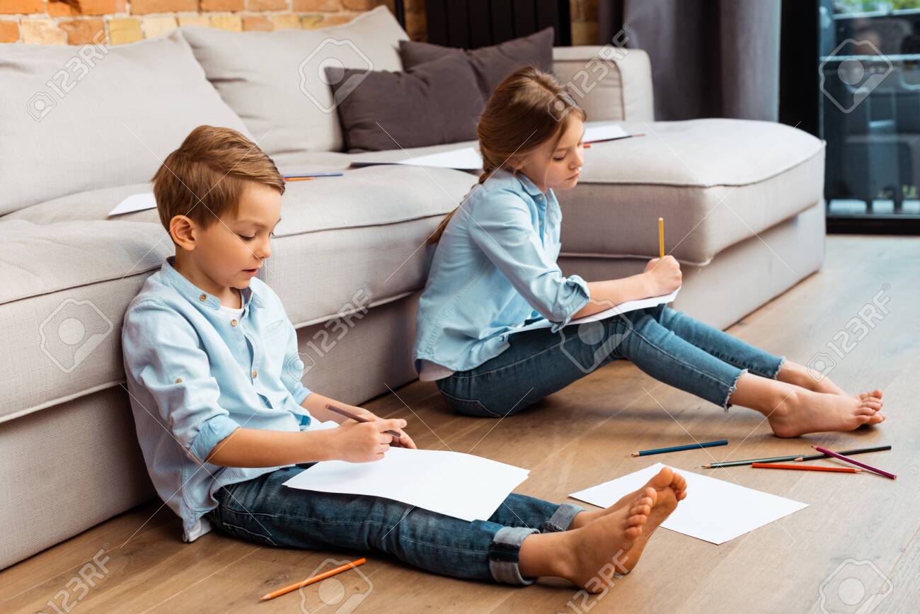 cute siblings sitting on floor and drawing in living room - 147503435 cute siblings sitting on floor and drawing in living room - 147503435