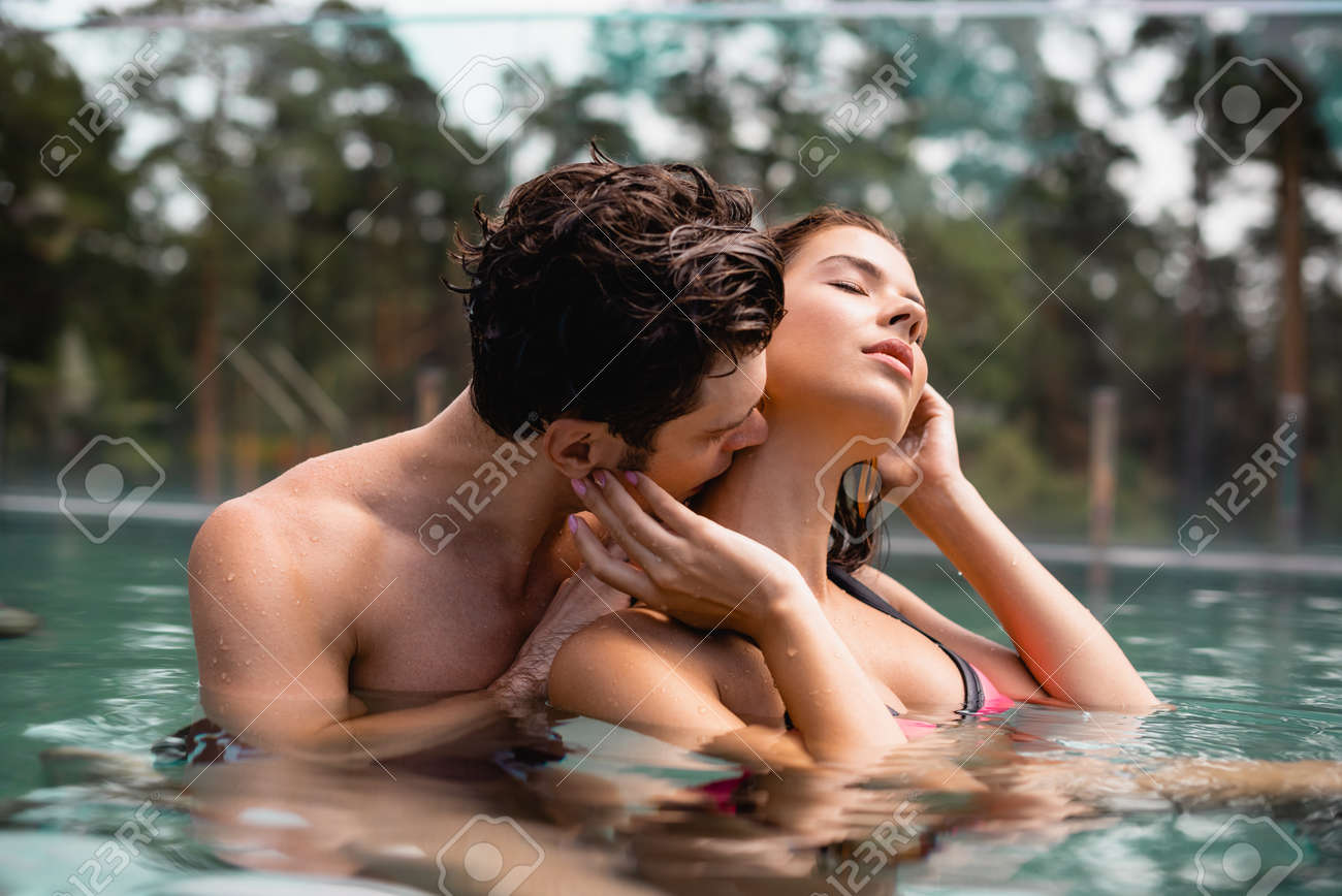 Muscular man kissing woman's neck passionately – sensual foreplay