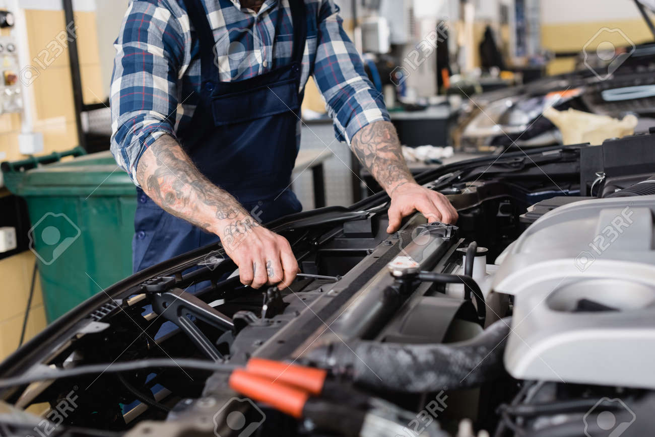 cropped view of mechanic checking car engine compartment in workshop on blurred foreground - 159530333 cropped view of mechanic checking car engine compartment in workshop on blurred foreground - 159530333