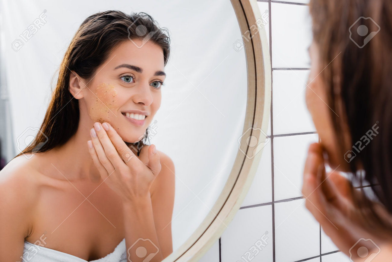 mulher de beleza aplicando máscara sob os olhos olhando-se no