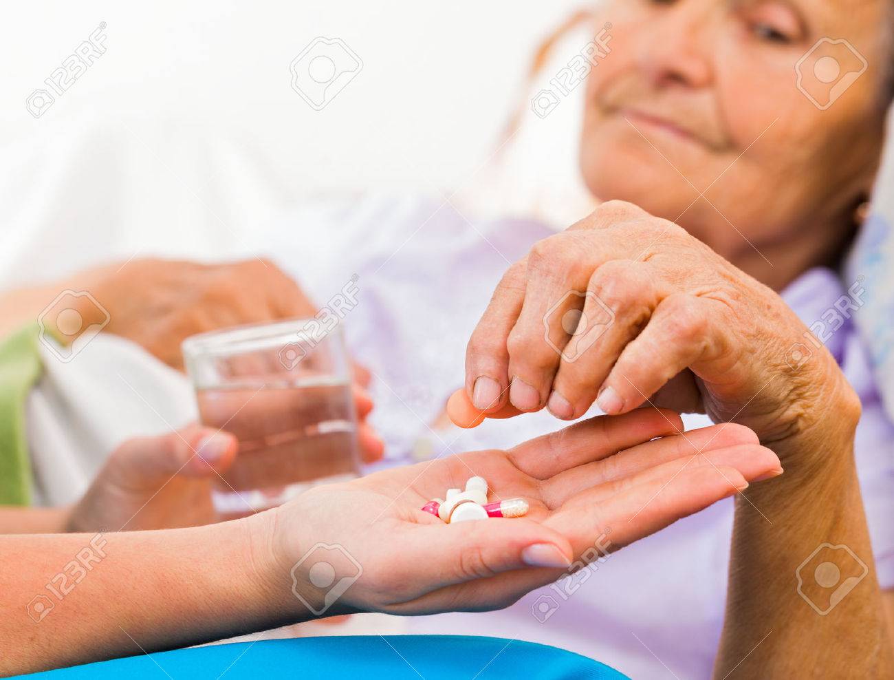Homecare nurse helping elderly lady to take her daily medicine. - 55422471 Homecare nurse helping elderly lady to take her daily medicine. - 55422471