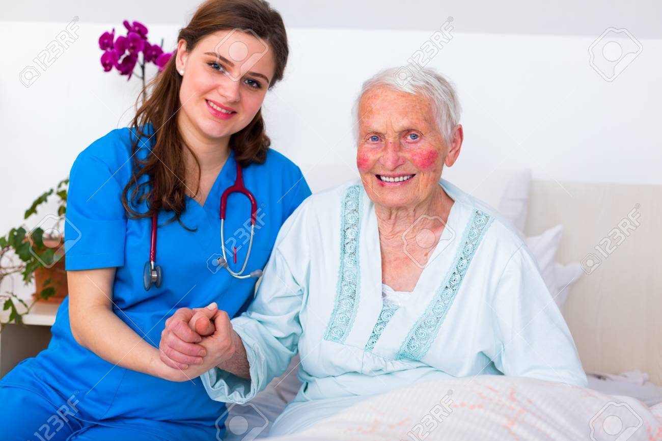 幸せな年配の女性は 思いやりのある看護師の彼女の 24 7 の監督と 設備の整った高級老人ホームのベッドに敷設します の写真素材 画像素材 Image