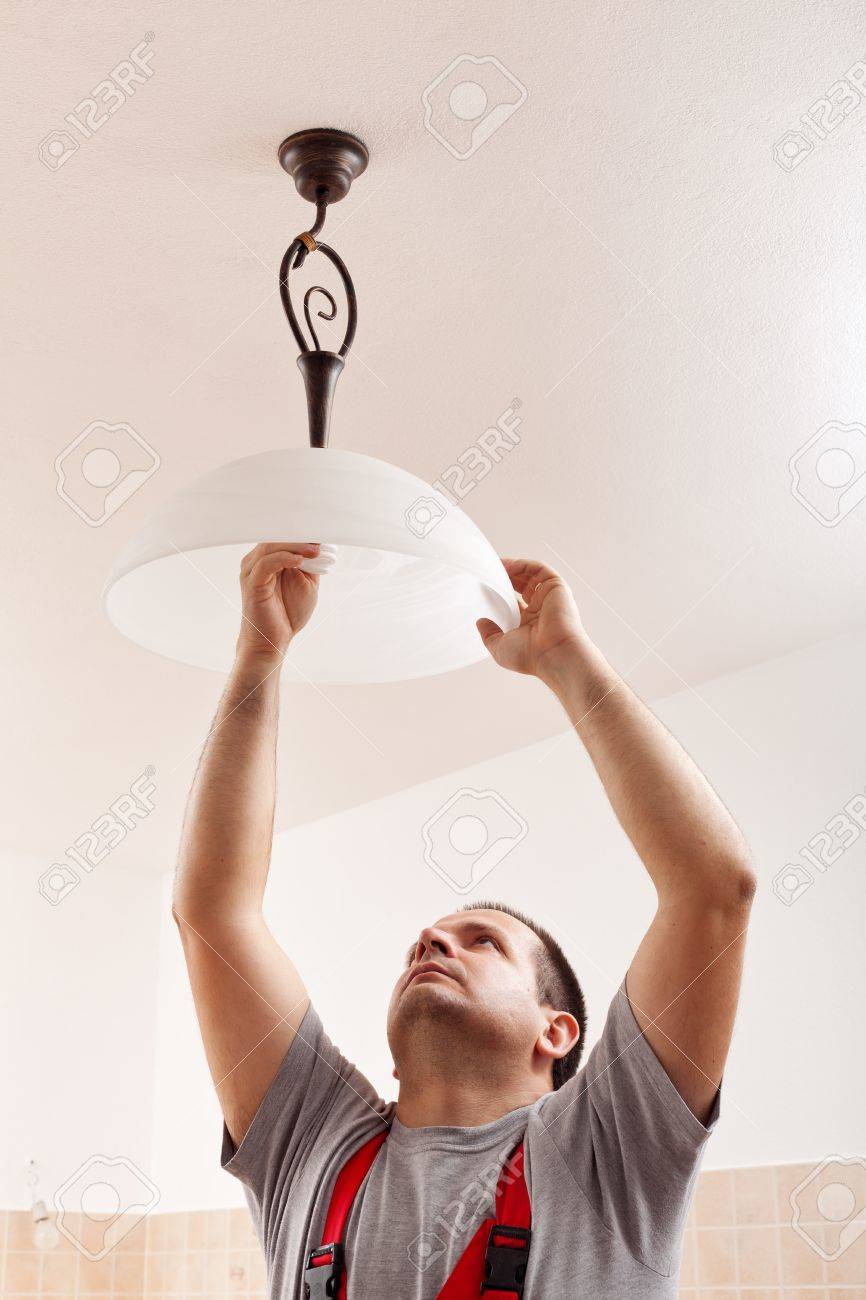 Electrician Man Screwing A New Lightbulb Into Ceiling Lamp