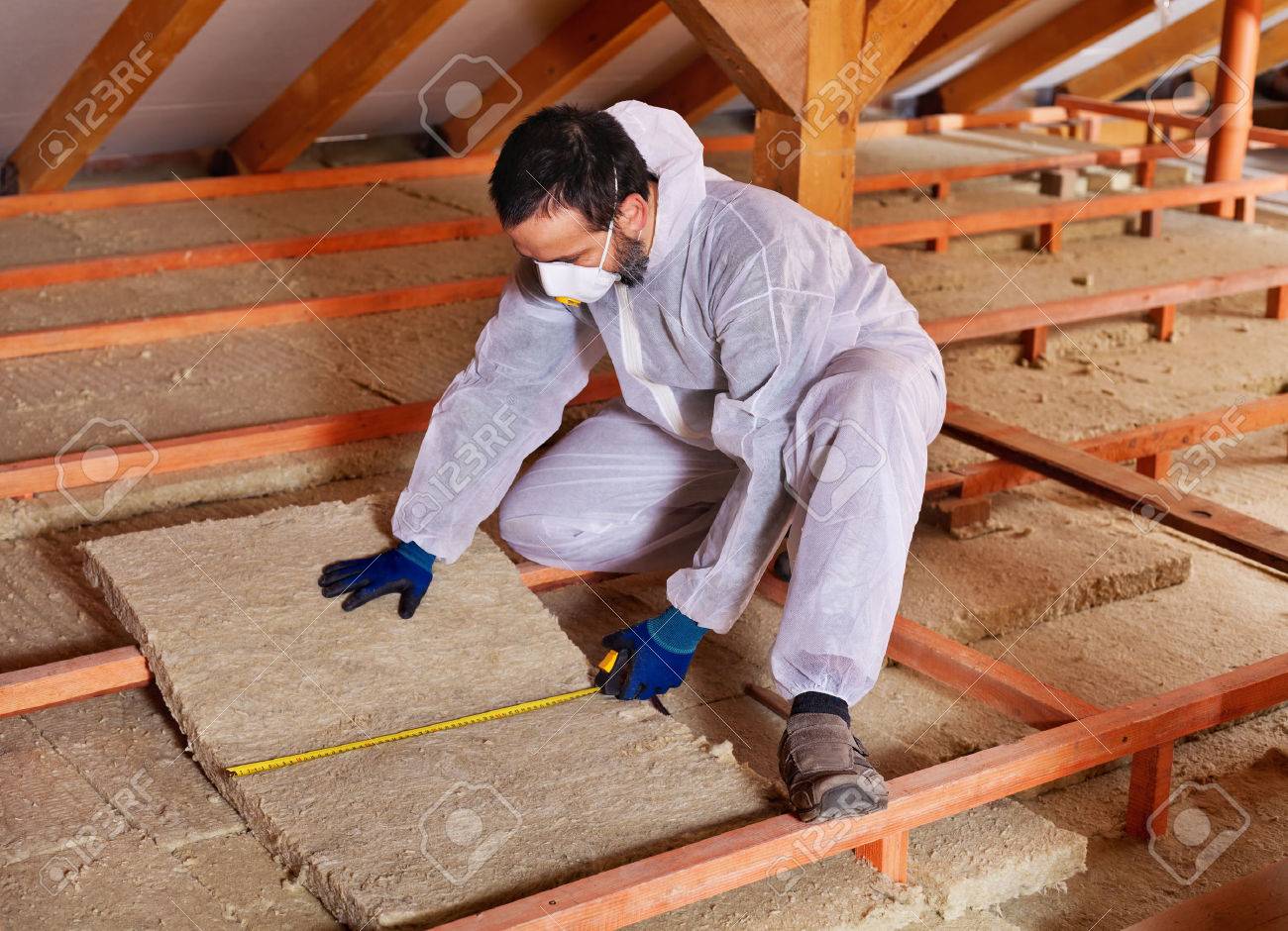 Man laying thermal insulation layer under the roof - measuring a mineral wool panel - 35647543 Man laying thermal insulation layer under the roof - measuring a mineral wool panel - 35647543