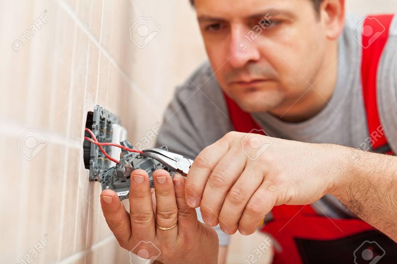 Electrician working on electrical wall fixture - inserting the wires, closeup - 37605882 Electrician working on electrical wall fixture - inserting the wires, closeup - 37605882