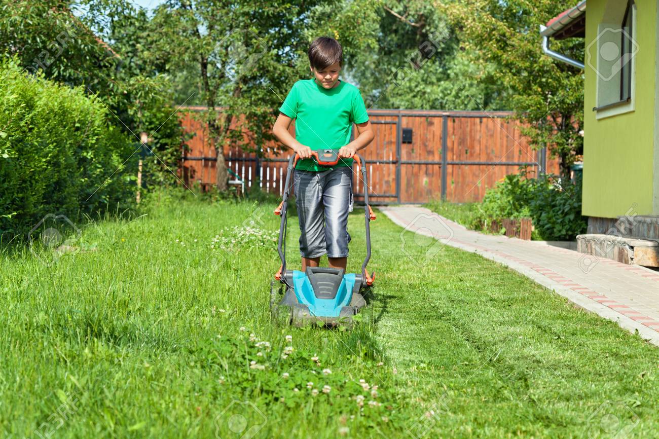 Boy cutting grass around the house in summertime - focusing on the operation - 54459021 Boy cutting grass around the house in summertime - focusing on the operation - 54459021