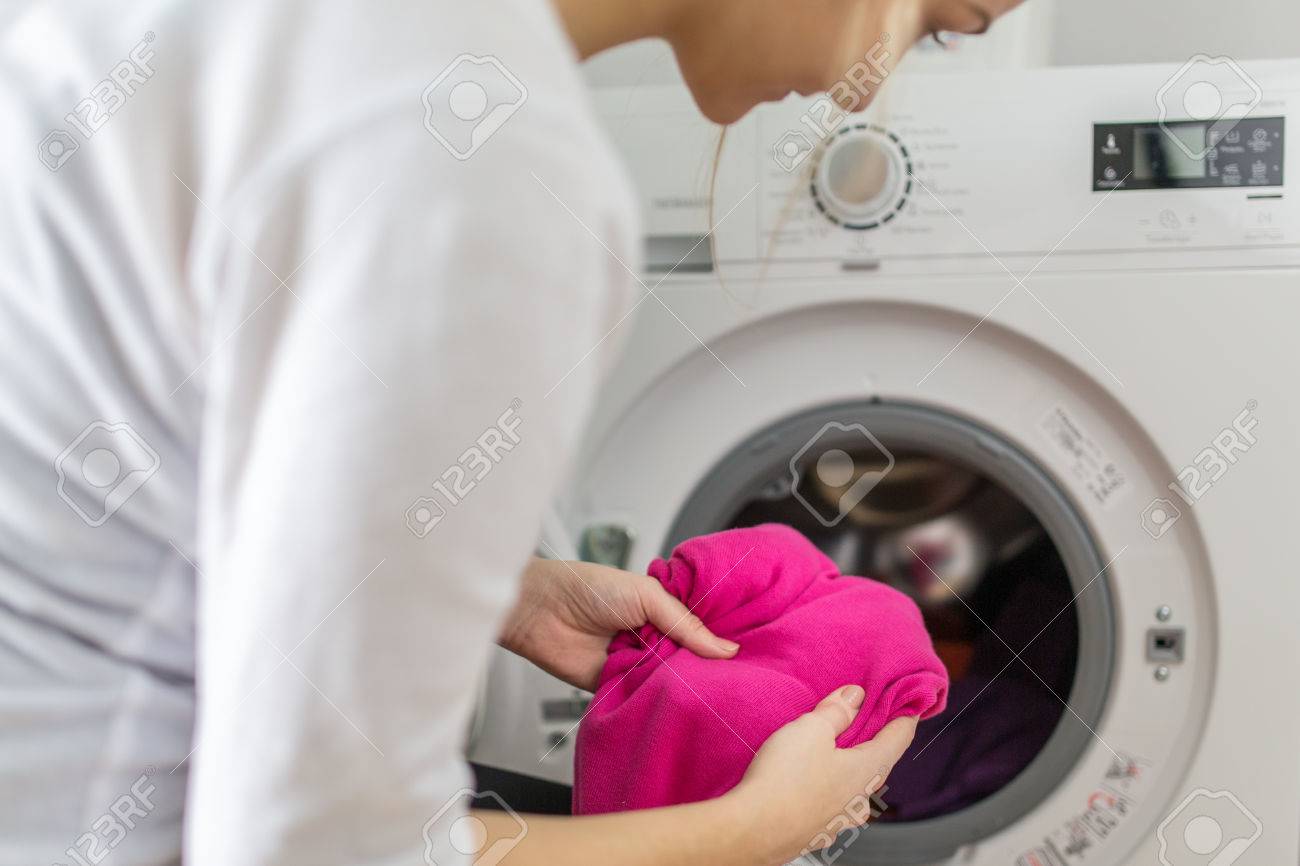 Housework: young woman doing laundry - putting colorful garments into the washing machine (shallow DOF; color toned image) - 51207166 Housework: young woman doing laundry - putting colorful garments into the washing machine (shallow DOF; color toned image) - 51207166