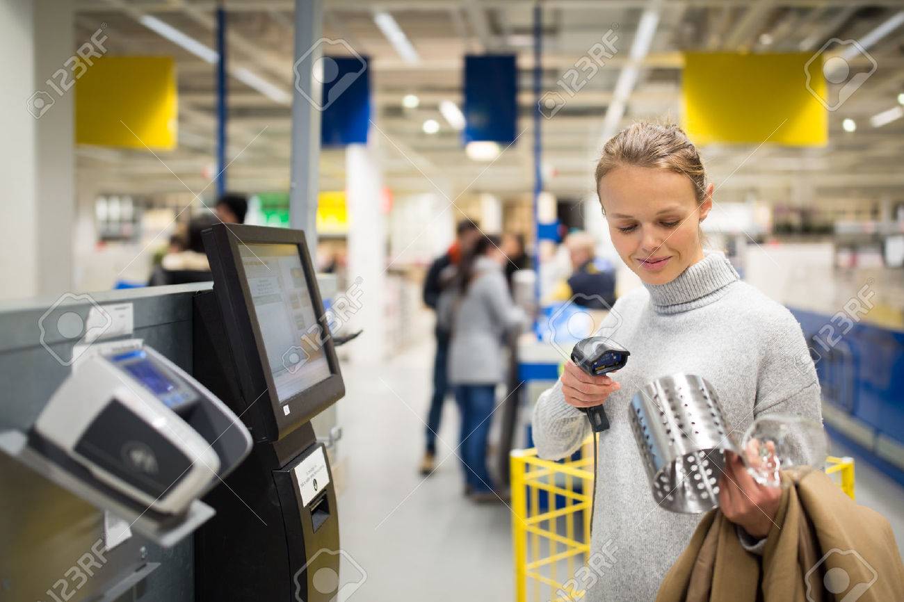 Pretty, young woman using self service checkout in a store (shallow DOF; color toned image) - 70168728 Pretty, young woman using self service checkout in a store (shallow DOF; color toned image) - 70168728