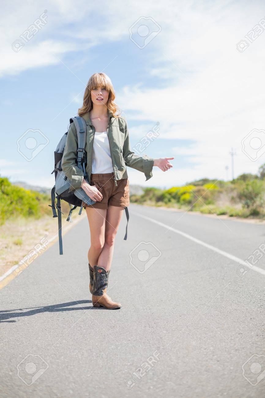 人けのない道でヒッチハイクをしながらポーズをとって自然なブロンドの女性 の写真素材 画像素材 Image