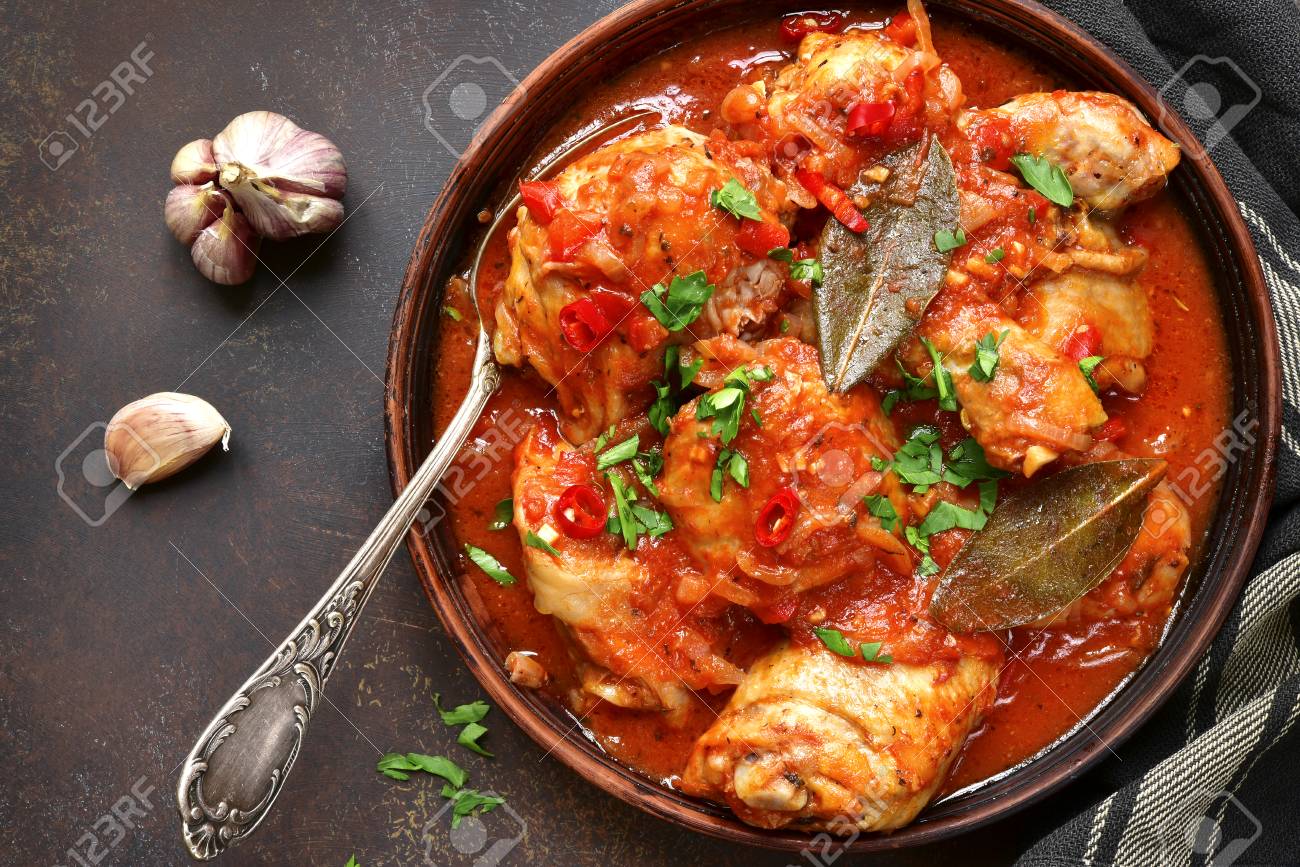 Chakhokhbili - chiken stew with cilantro (parsley) in tomato sauce in a clay bowl,traditional dish of georgian cuisine.Top view with copy space. - 74183065 Chakhokhbili - chiken stew with cilantro (parsley) in tomato sauce in a clay bowl,traditional dish of georgian cuisine.Top view with copy space. - 74183065