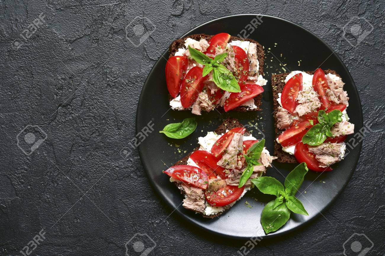 Rye sandwich with tomato,feta and tuna fillet on a black plate over dark slate,stone or concrete background.Top view with space for text. - 85702616 Rye sandwich with tomato,feta and tuna fillet on a black plate over dark slate,stone or concrete background.Top view with space for text. - 85702616