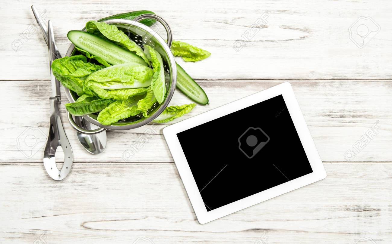 green salad vegetables with tablet pc on kitchen table internet