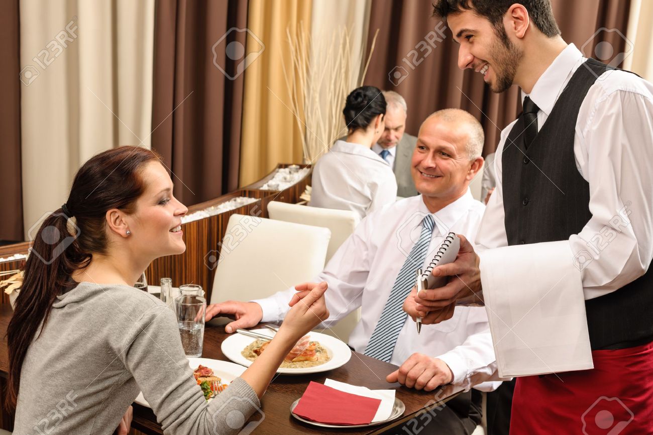 Business people served by waiter enjoy lunch at the restaurant - 13260146 Business people served by waiter enjoy lunch at the restaurant - 13260146