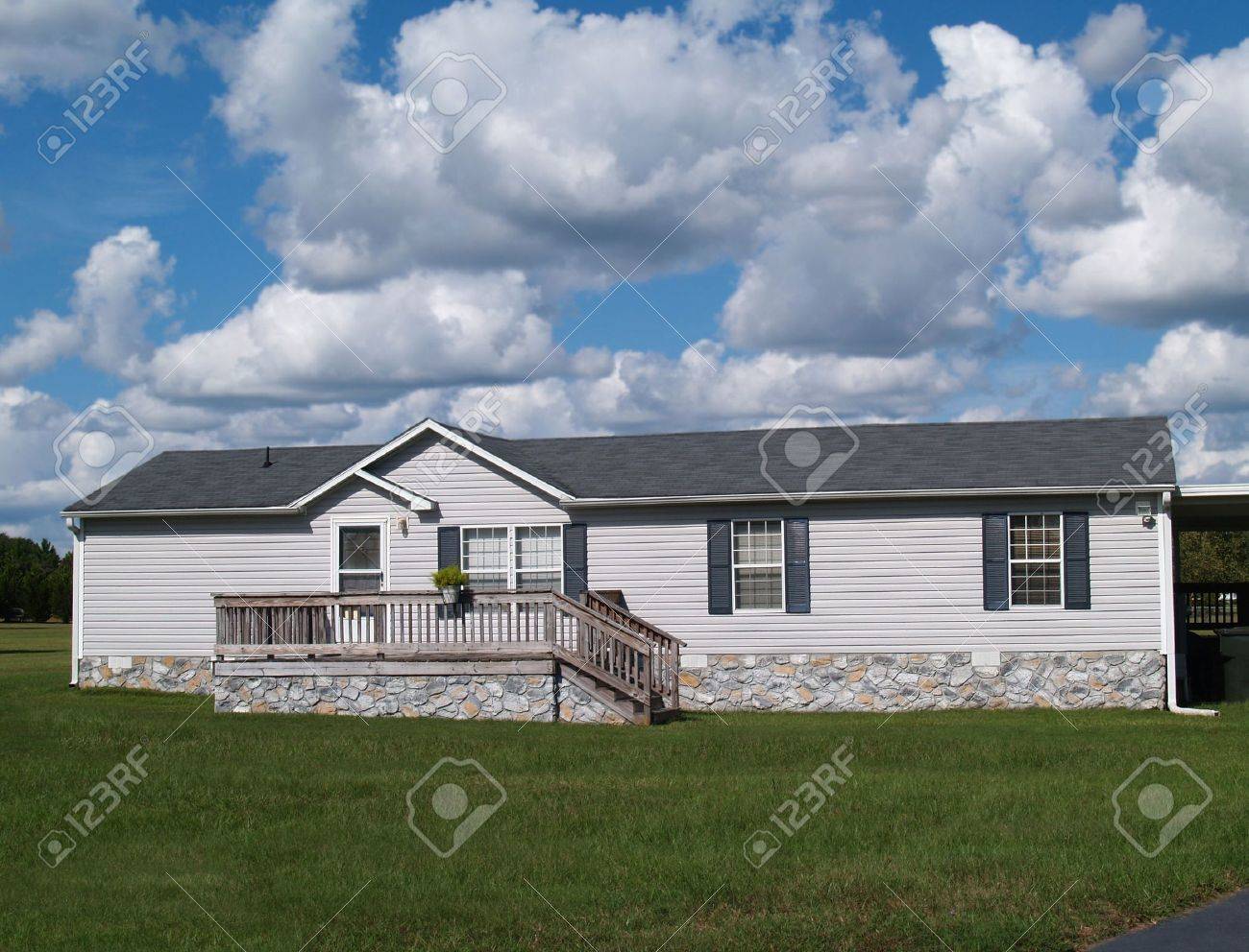Gray trailer home with stone foundation or skirting and shutters in front of a beautiful sky. - 6448195 Gray trailer home with stone foundation or skirting and shutters in front of a beautiful sky. - 6448195