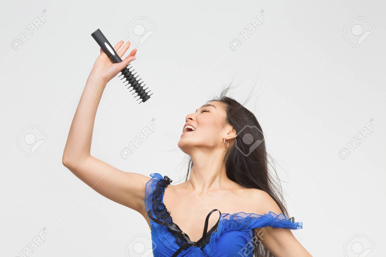 スタジオで歌を歌う青いランジェリーでファッションモデルをアジア 白い背景に彼女の前に魅力的なブルネット持株マイク の写真素材 画像素材 Image