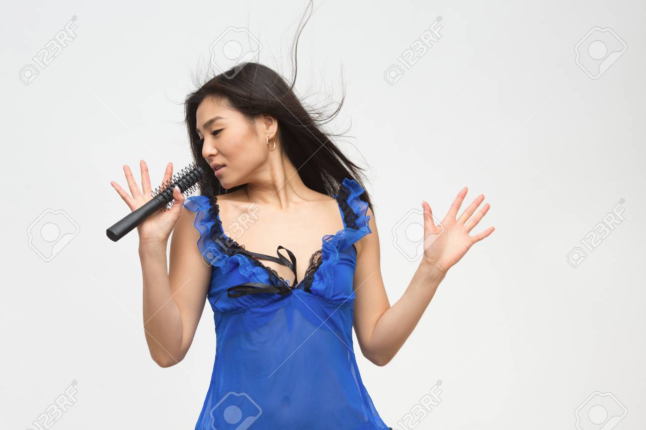 Retrato Del Modelo Asiático De La Moda Hermosa En Ropa Que Canta Canciones Mientras Que Sostiene El Micrófono Delante De Ella En Estudio. Fotos, Retratos, Imágenes Y De