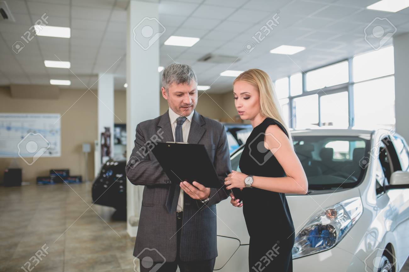 自動車ショールームの車ディーラーと若い女性 セールスマンは バイヤーへの技術的な情報表示 の写真素材 画像素材 Image 91007865