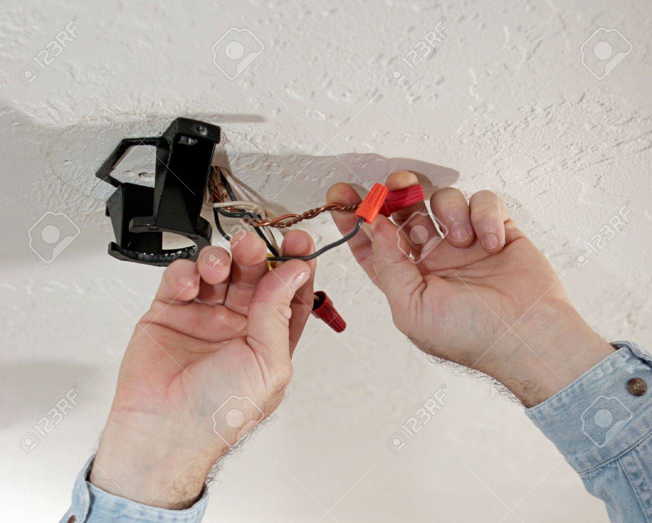 An Electrician Removing Wire Nuts From A Fan Assembly In The