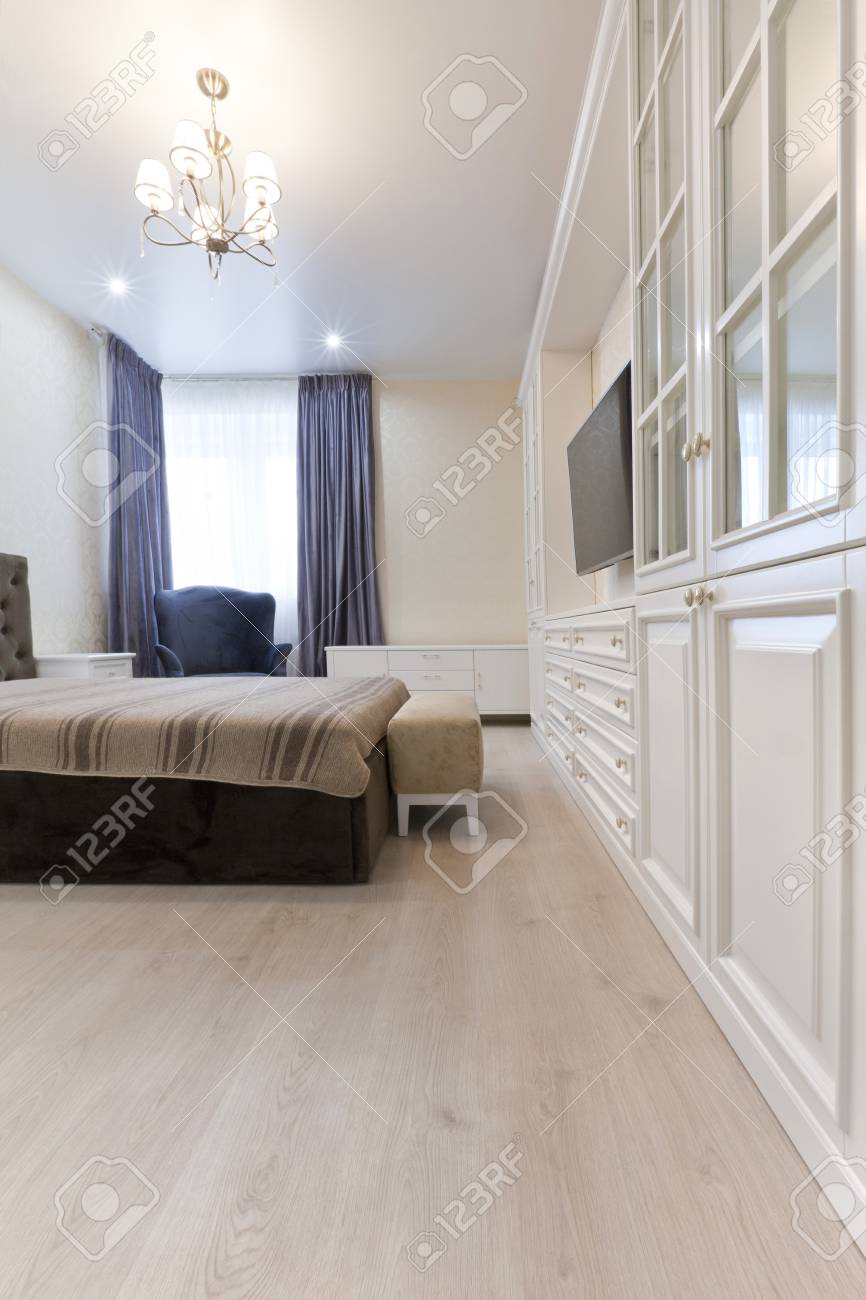 schlafzimmer in hellen farben mit dunklen bett und blauen vorhängen