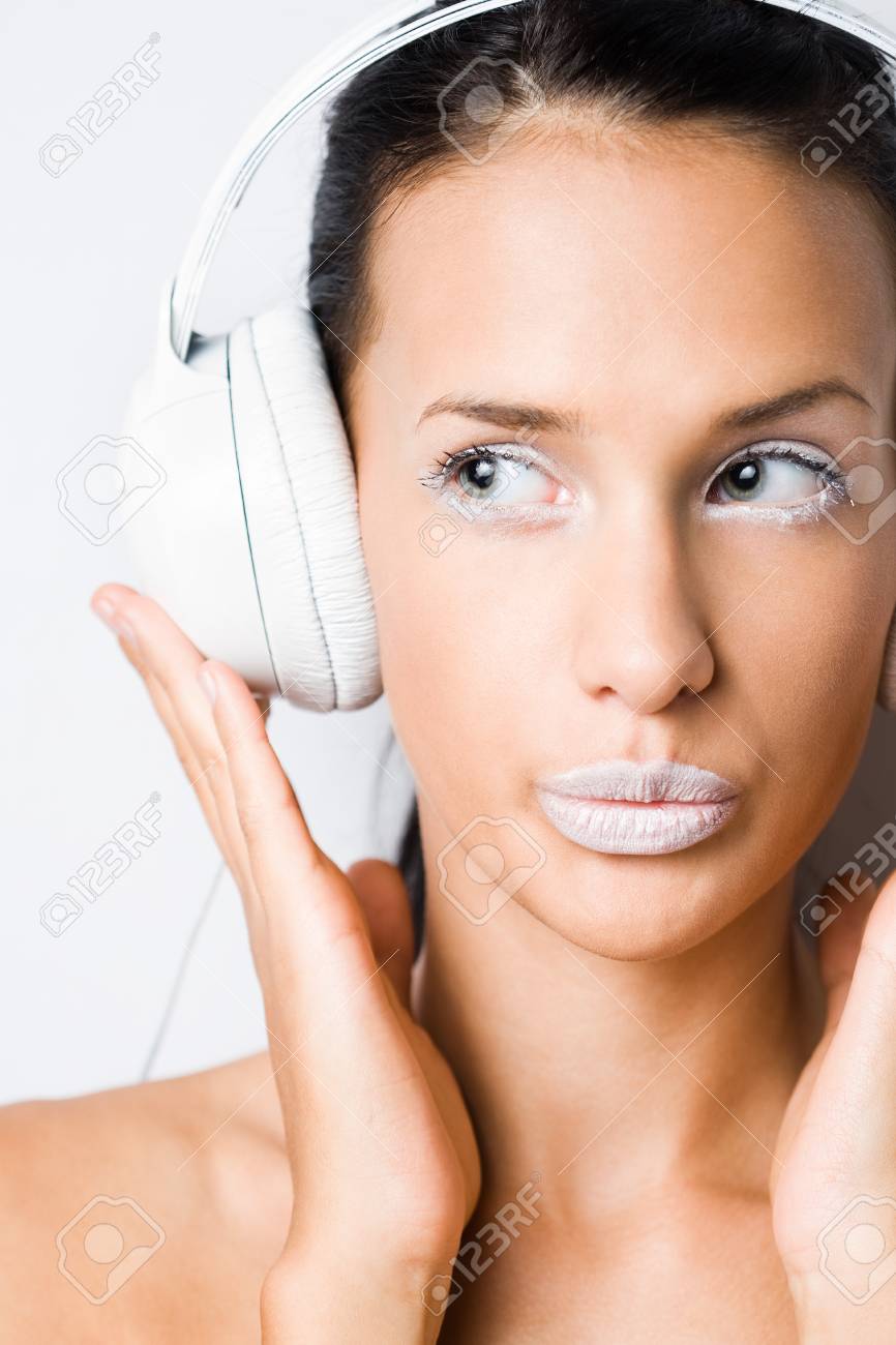 白いヘッドフォンで音楽を聴く白塗りメイクで若い日焼けブルネットの肖像画 の写真素材 画像素材 Image