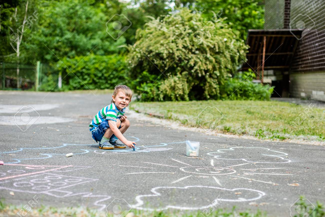 Cute Boy And Girl Drawing With Chalk On The Sidewalk In The Park