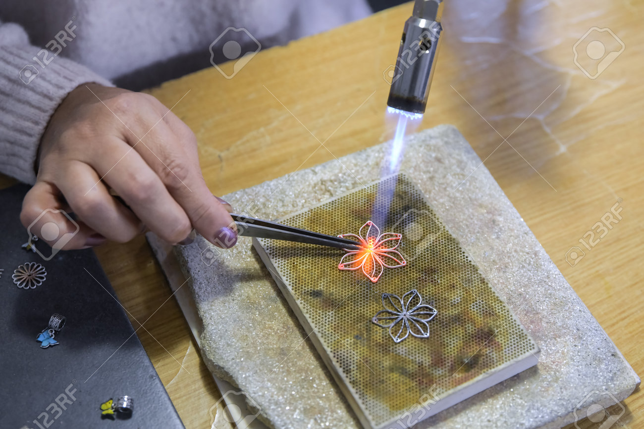 Burner heating in the production and repair of silver jewelry. Heating torch. A female artist makes handmade silver jewelry - 162278888 Burner heating in the production and repair of silver jewelry. Heating torch. A female artist makes handmade silver jewelry - 162278888