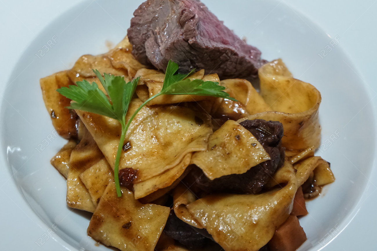 Baked pasta with sliced game meat seasoned with parsley, served on a plate - 163494955 Baked pasta with sliced game meat seasoned with parsley, served on a plate - 163494955