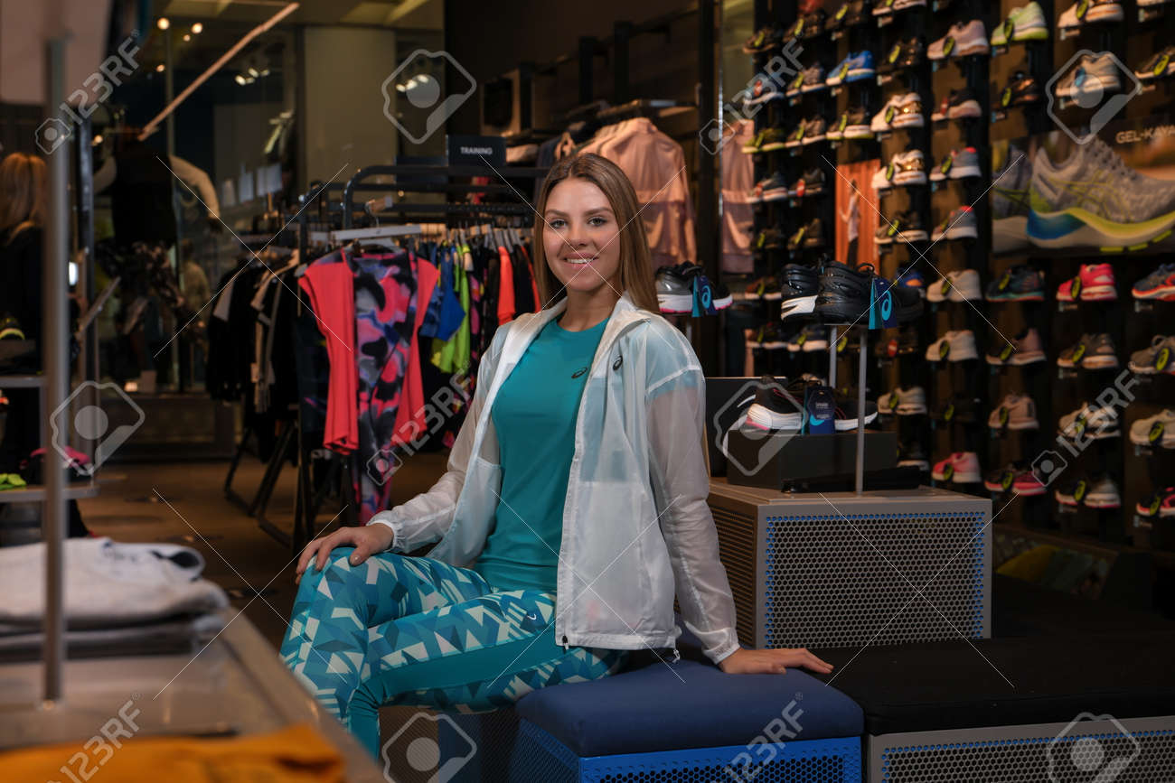 Skopje, Northern Macedonia - March 12, 2021: Asix store in Skopje, Northern Macedonia. Girl photo model dressed in sportswear and sneakers ASICS GEL, sitting and posing in a shop for sports equipment - 166164727 Skopje, Northern Macedonia - March 12, 2021: Asix store in Skopje, Northern Macedonia. Girl photo model dressed in sportswear and sneakers ASICS GEL, sitting and posing in a shop for sports equipment - 166164727