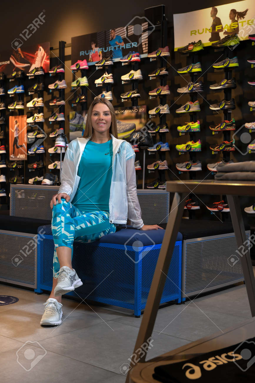 Skopje, Northern Macedonia - March 12, 2021: Asix store in Skopje, Northern Macedonia. Girl photo model dressed in sportswear and sneakers ASICS GEL, sitting and posing in a shop for sports equipment - 166164728 Skopje, Northern Macedonia - March 12, 2021: Asix store in Skopje, Northern Macedonia. Girl photo model dressed in sportswear and sneakers ASICS GEL, sitting and posing in a shop for sports equipment - 166164728