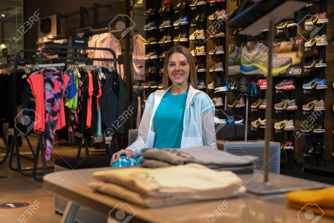 Skopje, Northern Macedonia - March 12, 2021: Asix store in Skopje, Northern Macedonia. Girl photo model dressed in sportswear and sneakers ASICS GEL, sitting and posing in a shop for sports equipment - 166164690 Skopje, Northern Macedonia - March 12, 2021: Asix store in Skopje, Northern Macedonia. Girl photo model dressed in sportswear and sneakers ASICS GEL, sitting and posing in a shop for sports equipment - 166164690