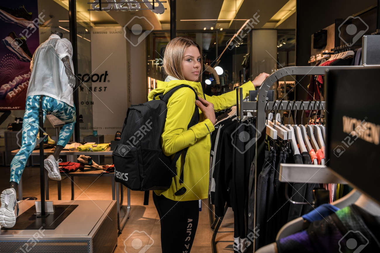 Skopje, North Macedonia - March 12, 2021: Asics store in Skopje, North Macedonia. Girl photo model wearing sports tracksuits and sneakers ASICS GEL, carrying a sports backpack on her shoulder - 166164680 Skopje, North Macedonia - March 12, 2021: Asics store in Skopje, North Macedonia. Girl photo model wearing sports tracksuits and sneakers ASICS GEL, carrying a sports backpack on her shoulder - 166164680