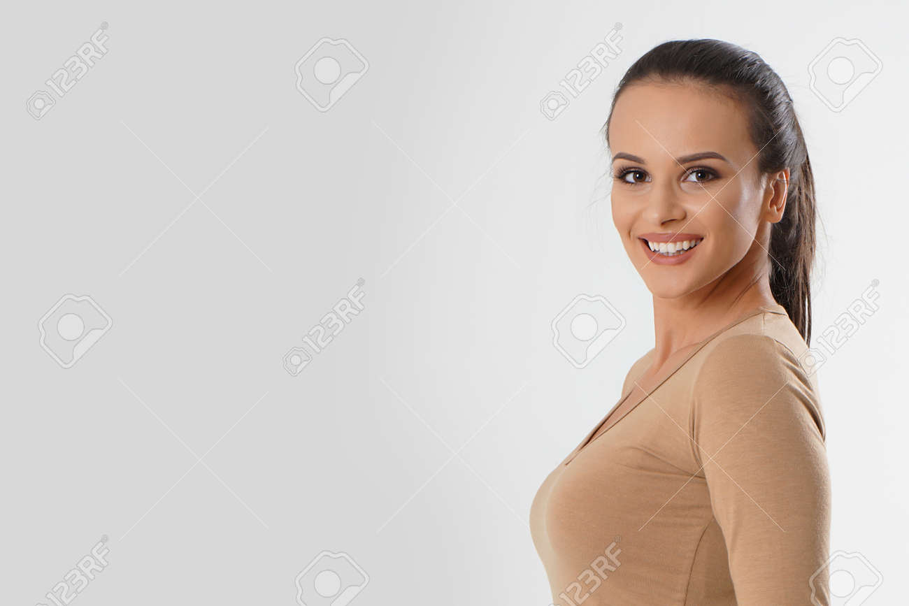 Portrait of young beautiful cute cheerful girl smiling looking at camera over white background. Woman portrait natural beautiful. Young attractive smiling woman in brown blouse looking at camera - 166482598 Portrait of young beautiful cute cheerful girl smiling looking at camera over white background. Woman portrait natural beautiful. Young attractive smiling woman in brown blouse looking at camera - 166482598