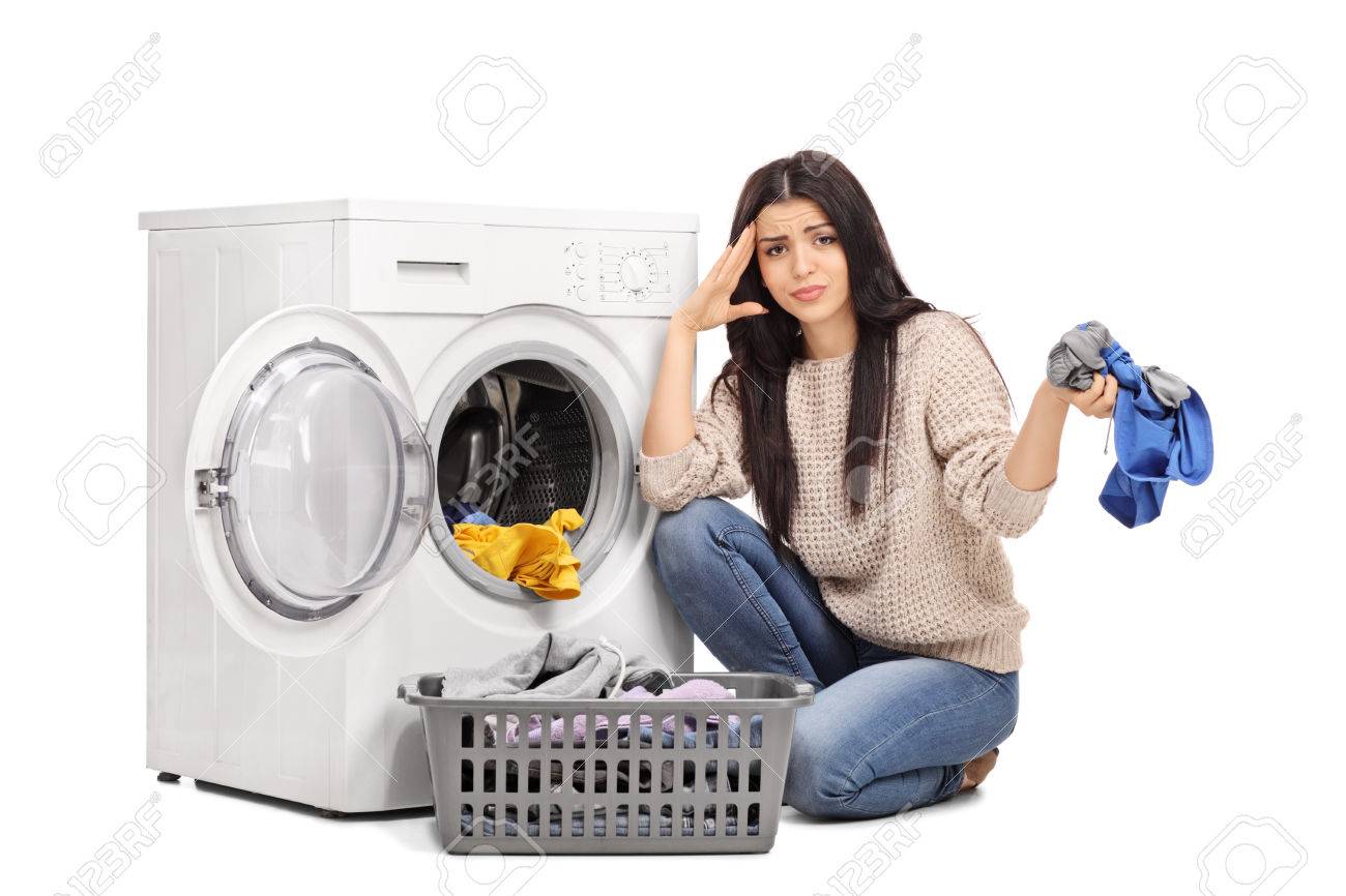 Studio shot of a sad woman emptying a washing machine and looking at the camera isolated on white background - 50659132 Studio shot of a sad woman emptying a washing machine and looking at the camera isolated on white background - 50659132