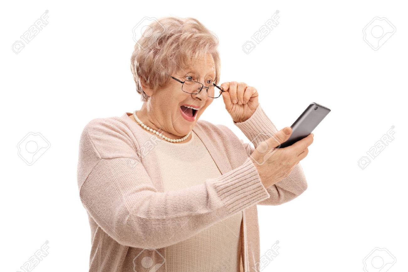 Excited senior looking at a phone isolated on white background - 72995987 Excited senior looking at a phone isolated on white background - 72995987