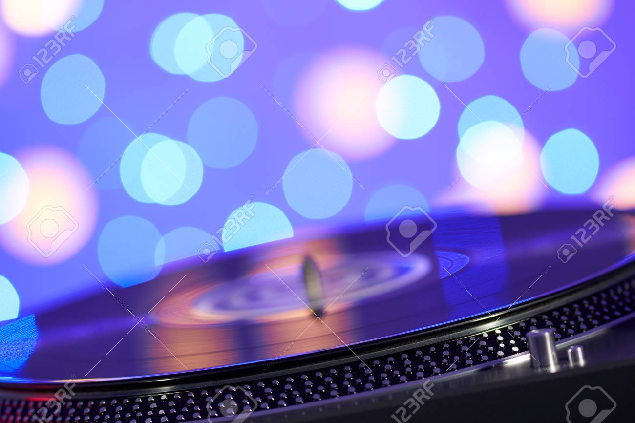 Turntable vinyl record player. Sound technology for DJ to mix & play music. Vintage vinyl record player on a background decorations for a party, bright disco lights. Needle on a vinyl record - 97761277 Turntable vinyl record player. Sound technology for DJ to mix & play music. Vintage vinyl record player on a background decorations for a party, bright disco lights. Needle on a vinyl record - 97761277