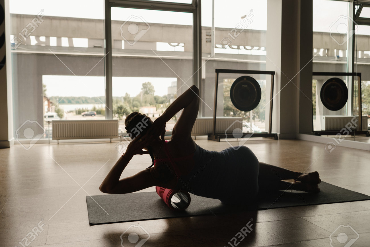 床に大きなマッサージローラーでヨガをしているスレンダーの女の子。の写真素材・画像素材 Image 217780512