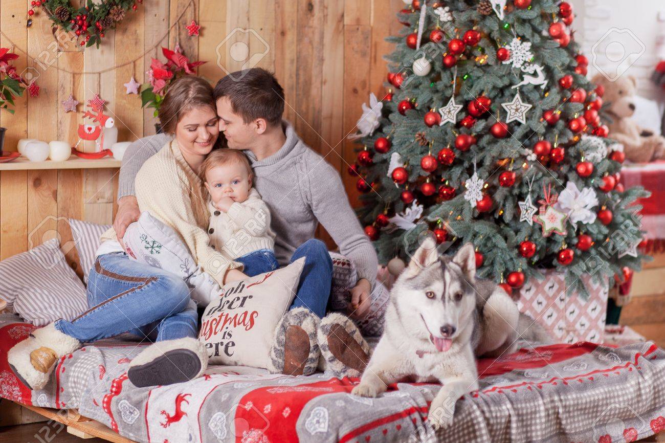 Happy family and a dog Siberian Husky near the fireplace around..