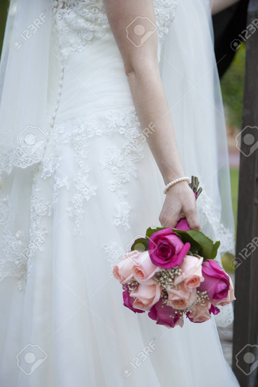 Detail Of The Bridal Bouquet In Salmon And Pink Colors Which Holds The Bride Placed On Her Back Wearing Her White Dress Stock Photo Picture And Royalty Free Image Image 98975161